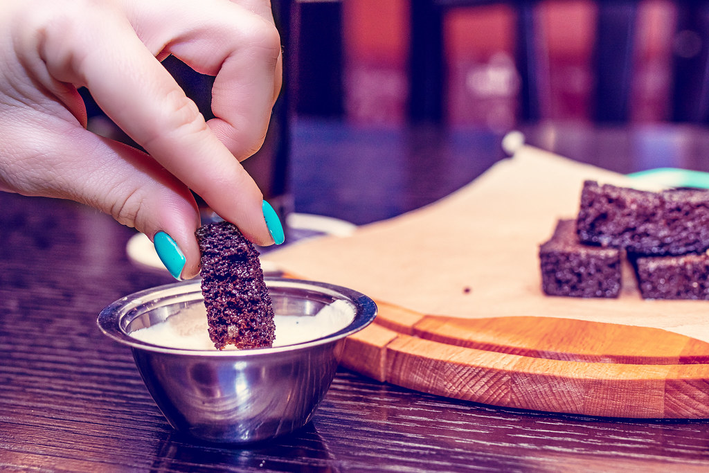 A hand reaching across a pub table set with snacks and drinks